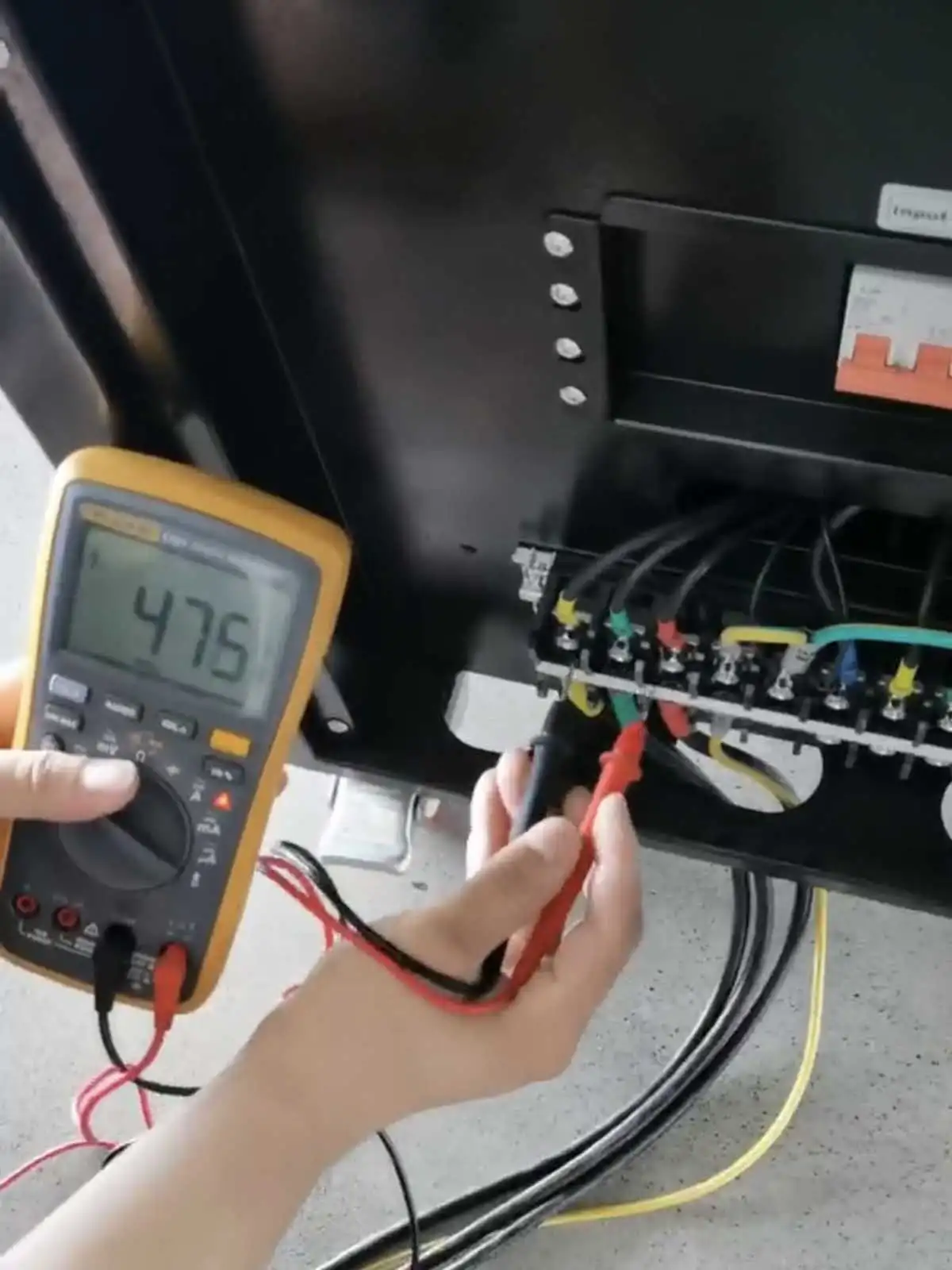 Handheld meter measuring approximately 475V at the WVFP-33020 input terminals during factory testing.