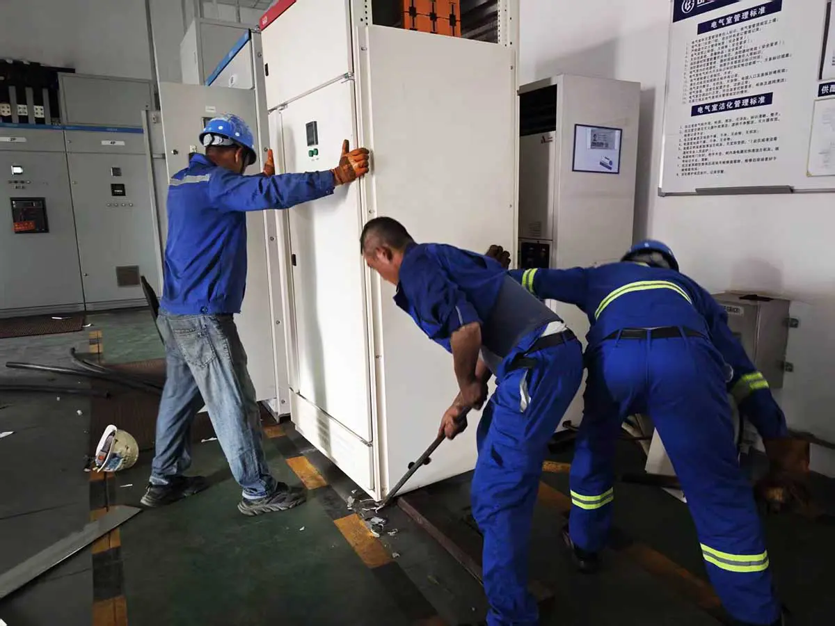 Installation team positioning an isolation transformer cabinet beside the existing LV switchgear