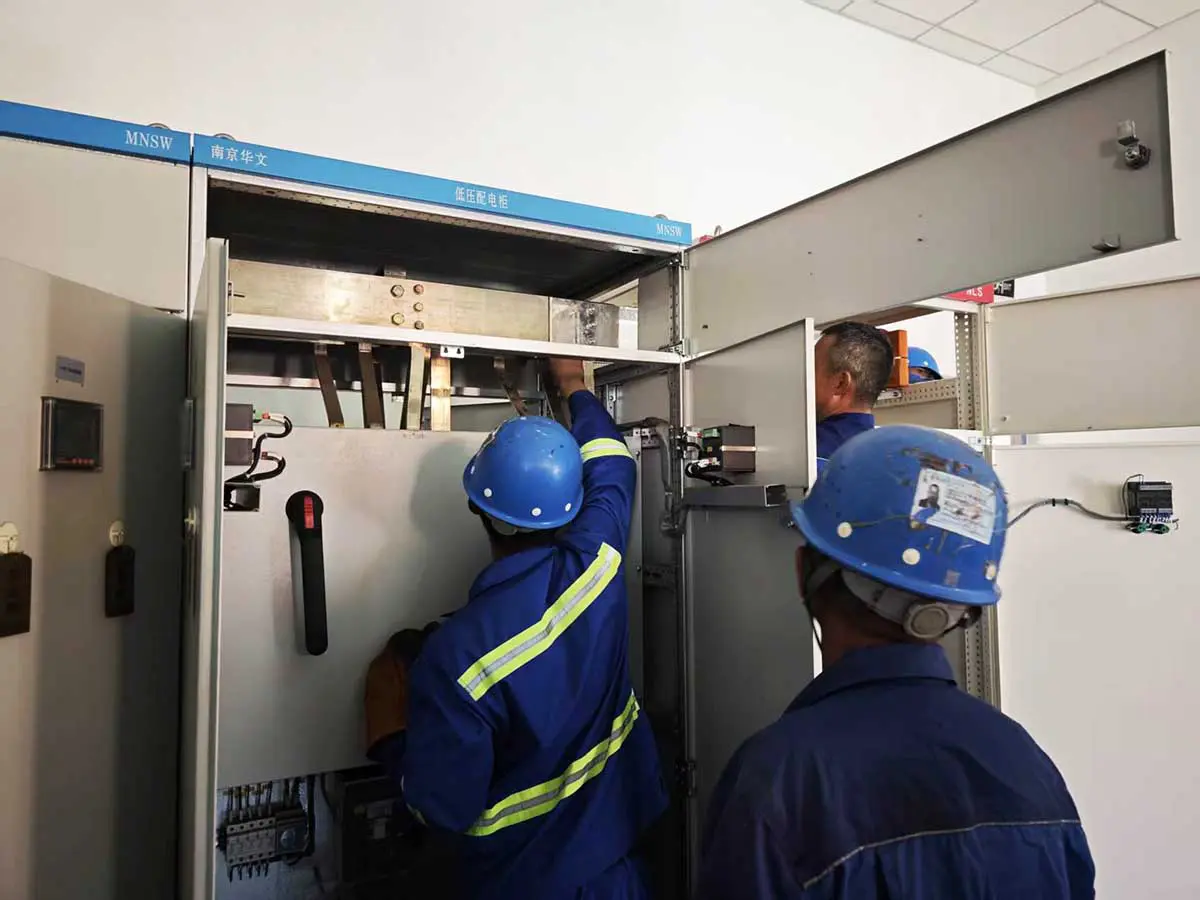 Engineers completing the copper-busbar connection between adjacent cabinet sections